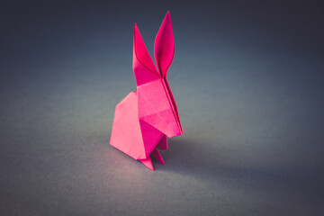 Pink paper rabbit origami isolated on a grey background