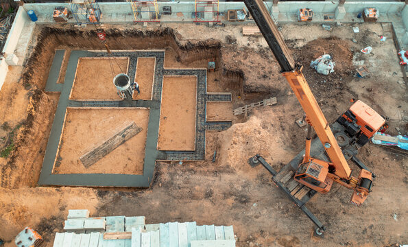 Foundation of future house. Pouring foundation with cement on construction site with crane, aerial view.