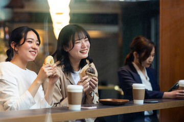 カフェでドーナツを食べる若い女性