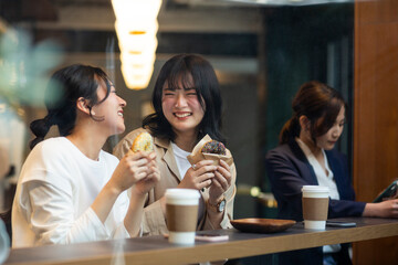 カフェでドーナツを食べる若い女性