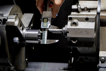 Fototapeta na wymiar Hands of an engineer measures a metal part with a digital vernier caliper. Quality control of part machined on a lathe,Quality control concept of Qc.
