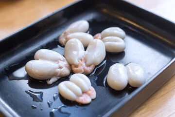 Fresh squid eggs in a black tray for grilling, delicious taste.