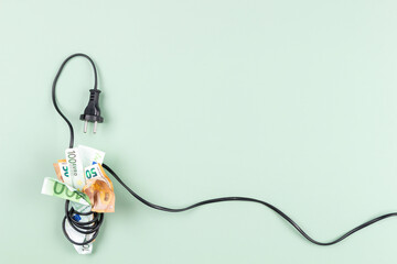 Euro banknotes are tightly wrapped with electric power cable cord. Energy efficiency, power consumption, rising electricity price and expensive energy concept