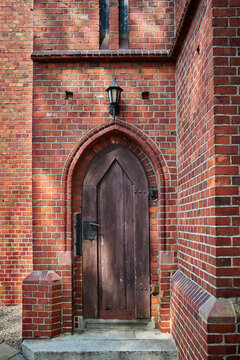 Wooden gates in a side entrance in an old church built of red brick.