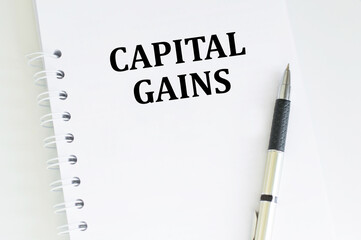 Capital gains text on a notepad on a table next to a pen