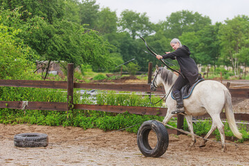 Obraz premium beautiful woman with long hair woman on a horse shooting a bow in training