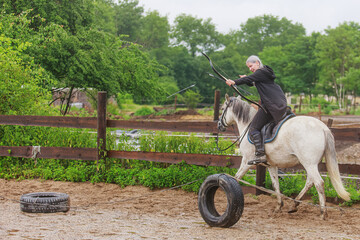 beautiful woman with long hair woman on a horse shooting a bow in training