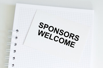 SPONSORS WELCOME Text written on a card with notebook and clipboard, grey background