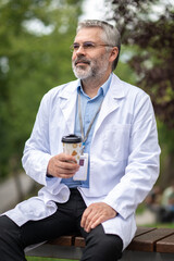 Bearded mature man in na lab coat with a cup of coffee