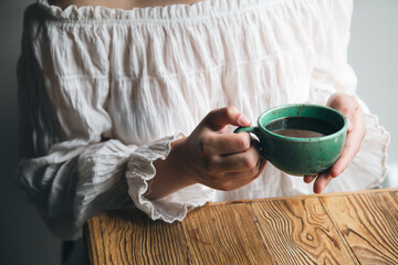 Fototapeta na wymiar Close-up, green cup with coffee in female hands.