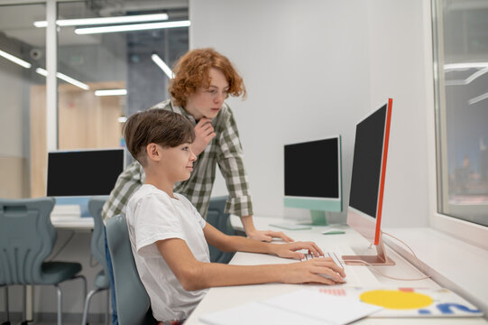 Schoolboys working on computers at IT lesson at school - Powered by Adobe