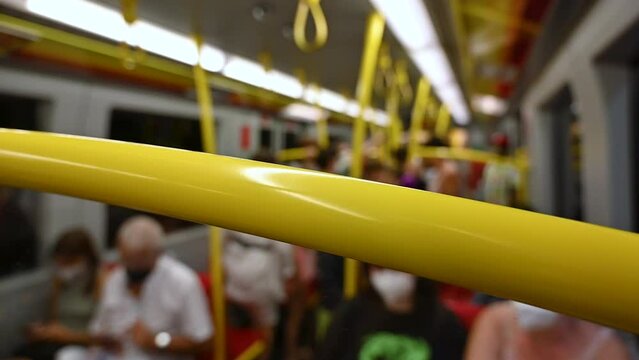 Vienna, Austria, August 2022. Slow motion footage with blurred conceptual image inside a subway car. The figures of the people sitting can be recognized, the yellow supports are highlighted.