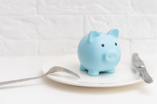 Piggy bank on the plate with fork and knife.