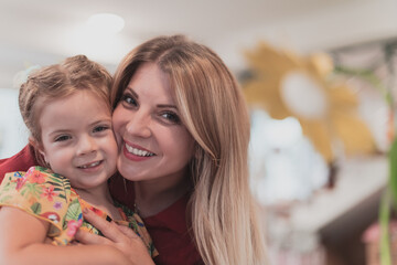 A cute little girl kisses and hugs her mother in preschool