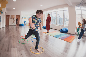 Small nursery school children with female teacher on floor indoors in classroom, doing exercise....
