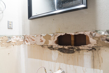 Damaged drywall under the mirror in bathroom with broken plasterboard and mold, mildew, water...