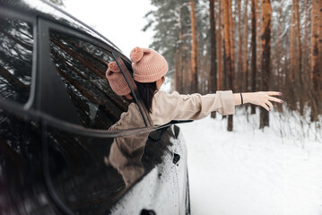 Rear view of girl in car over snowy forest on winter roadtrip
