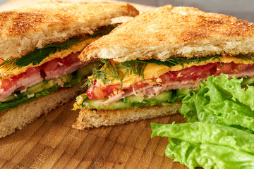 Two greens sandwiches on a wooden board in close-up. The concept is a delicious breakfast