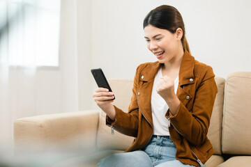 Beautiful young women using mobile phone sitting on sofa in living room. Using smartphone. Woman Shopping online store. Relax time at home