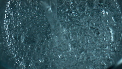 Bubbling water pouring glass top view. Closeup air bubbles rising exploding
