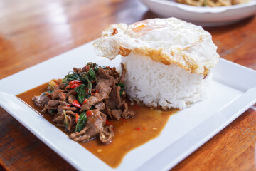 Stir fried beef with basil with fried egg on white plate  It's a simple a la carte.  that Thai people are very popular.