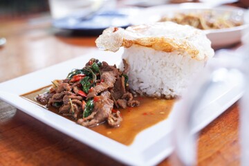 Stir fried beef with basil with fried egg on white plate  It's a simple a la carte.  that Thai people are very popular.