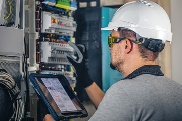 Man, an electrical technician working in a switchboard with fuses.