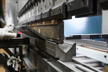 Bending machine operates with heavy metal plate in shop