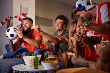 Football fans cheering while watching the game on TV