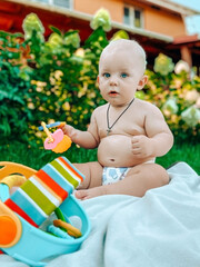 Cute baby boy sitting outdoors playing with the toys