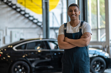 Joyful mechanic standing in his auto workshop