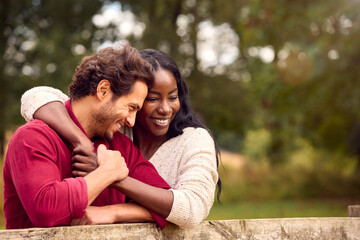 Loving Mixed Race Couple Leaning On Fence On Walk In Countryside