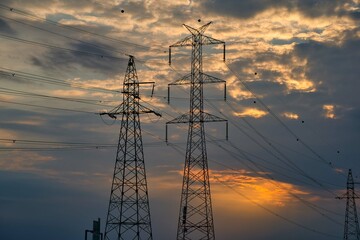 High Voltage Electric Pylons And Electrical Wires on the sunset background. Electricity Poles. Power And Energy - obrazy, fototapety, plakaty