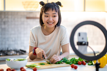 Smiling housewife preparing a vegetable salad in her cookery vlog