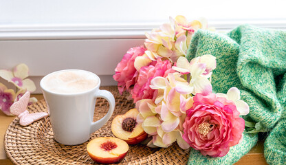 Home composition with a cup of coffee, flowers and a knitted element.
