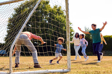 Multi-Generation Family At Home In Garden Playing Football Or Soccer Together