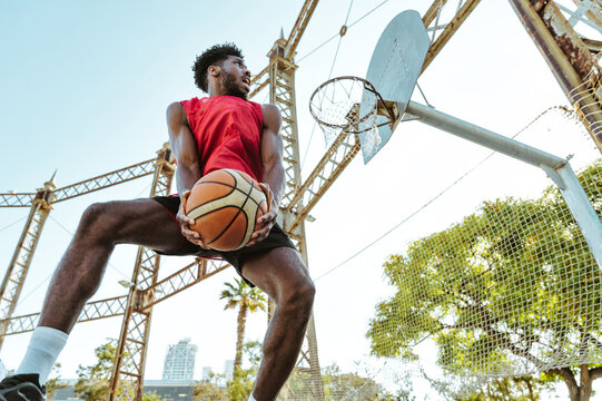 One vs one basketball game training at the court. Cinematic look image of friends practicing shots and slam dunks in an urban area