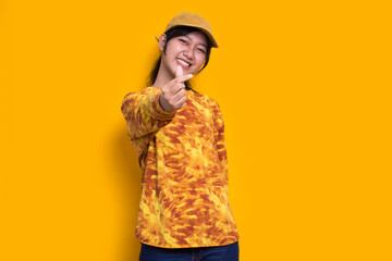 asian beautiful young woman showing heart sign love isolated on yellow background
