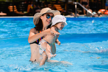 Obraz na płótnie Canvas Mother and toddler girl swim in pool