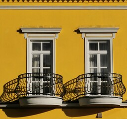Obraz premium vivid yellow pointed house in Sarajevo Bosnia, with intricate wrought-iron balcony and stylish white window frames