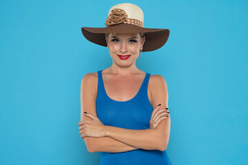 Smiling young woman with brown summer hat on a blue background