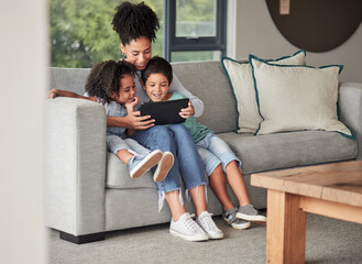 A mother with children on couch with tablet to watch educational shows and streaming music. Foster...