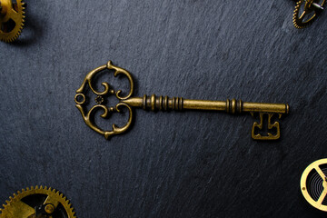 Old vintage key and metal gears dark background.