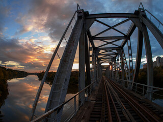 Old iron bridge across the river, autumn landscape at sunset