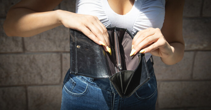 Young woman holding empty wallet. No Money