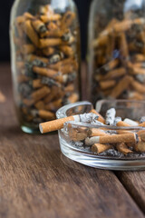 Many cigarette stubs and ash in a glass ashtray