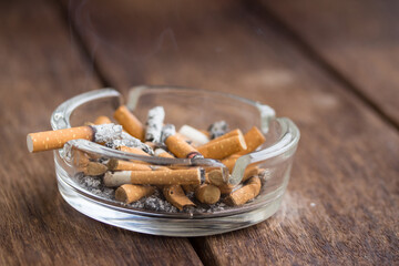  Many cigarette stubs and ash in a glass ashtray