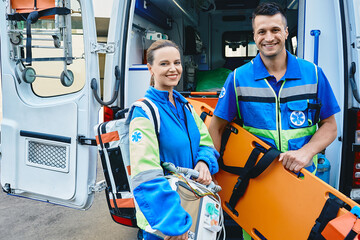 Emergency medical technicians standing near ambulance. Personnel of emergency service with first aid medical equipment - Powered by Adobe