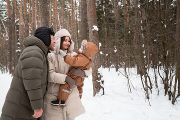 Parents walking with child in winter forest or park
