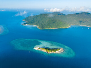 Stunning aerial high angle view of Black Island with a beautiful reef and Hook Island in the background, both part of the Whitsunday Islands group near the Great Barrier Reef in Queensland, Australia.